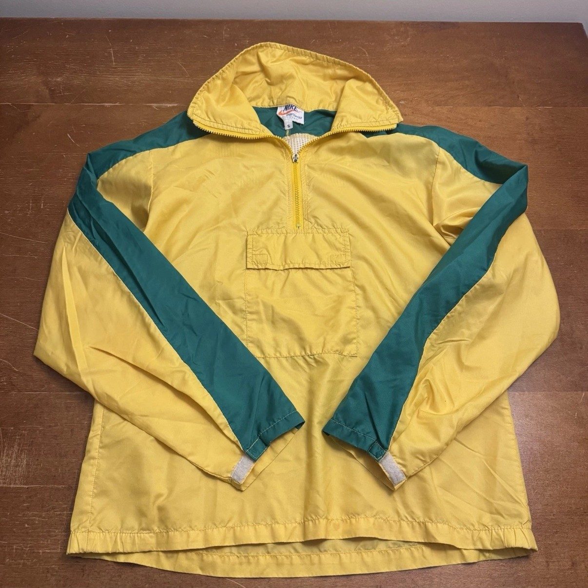 Vintage Nike Orange Tag anorak — front view: yellow pullover windbreaker with green shoulder panels, half-zip and kangaroo pouch, laid flat