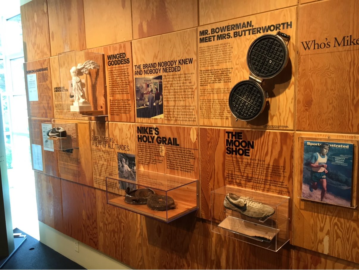 The Nike history wall at Nike Headquarters — wooden panels, Bowerman's waffle iron, the Moon Shoe case and the 1970 Sports Illustrated cover