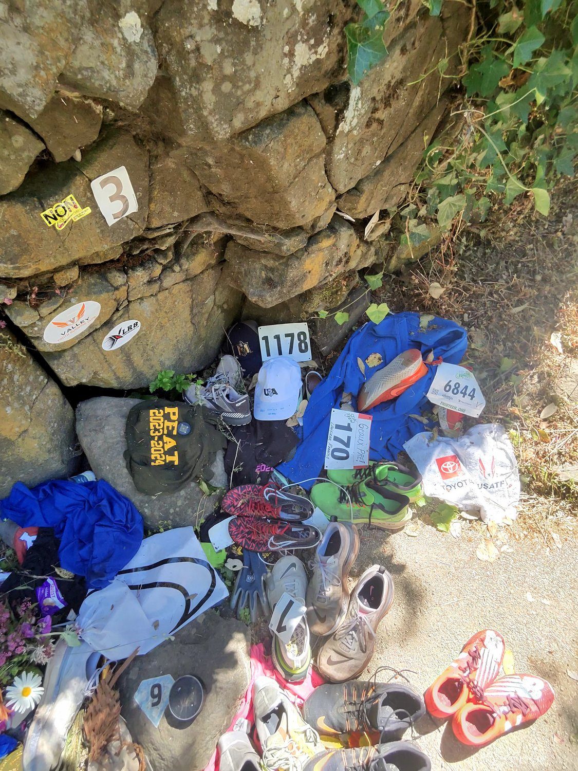 Running shoes, spikes and race bibs left at the base of Pre’s Rock during the 2024 U.S. Olympic Trials