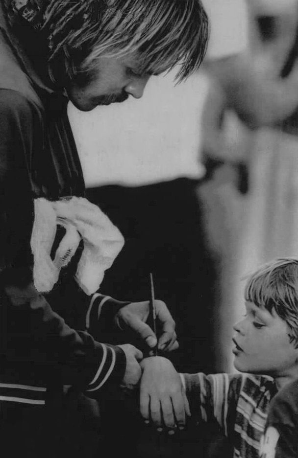 Steve Prefontaine leaning down to sign an autograph for a young fan, 1975